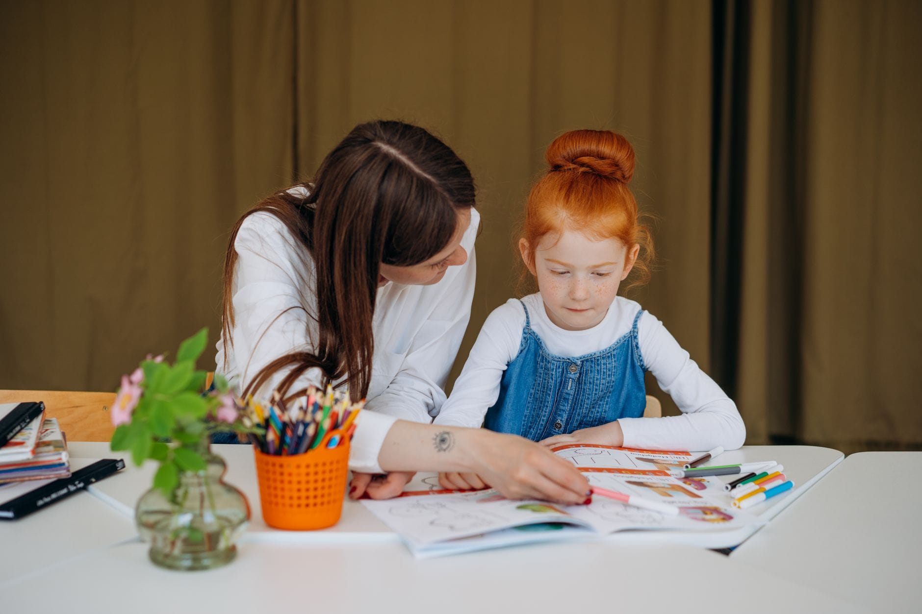 Nauczycielka wspiera małą dziewczynkę podczas zadania edukacyjnego w klasie