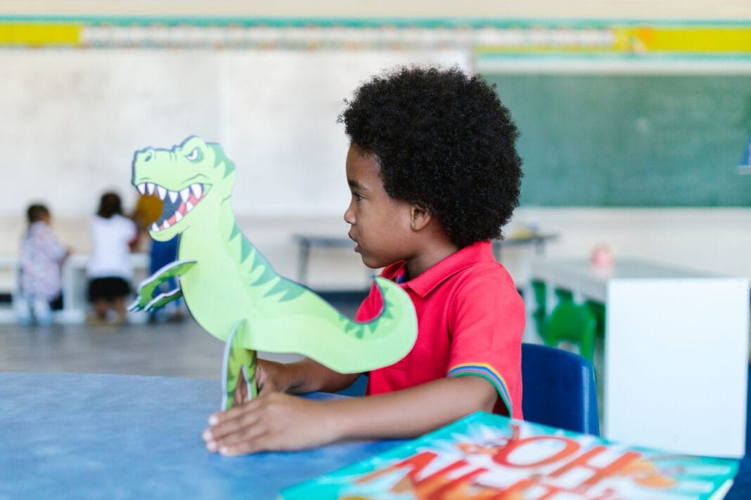 Przedszkolak bawi się zabawkowym dinozaurem w klasie