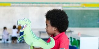 Przedszkolak bawi się zabawkowym dinozaurem w klasie