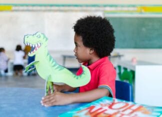 Przedszkolak bawi się zabawkowym dinozaurem w klasie