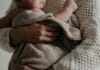 Mama tuląca niemowlę owinięte kocykiem w ciepłym uścisku