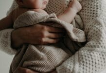 Magiczne skoki rozwojowe u niemowląt jak je rozpoznać i wspierać Mama tuląca niemowlę owinięte kocykiem w ciepłym uścisku
