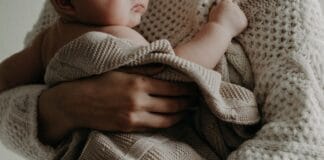 Mama tuląca niemowlę owinięte kocykiem w ciepłym uścisku