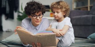 Mama z małym synem czytają razem książkę na dywanie