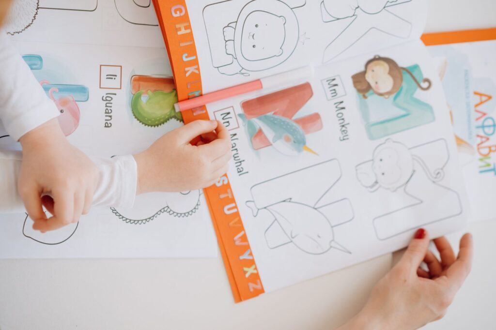 Dzieci uczą się alfabetu, kolorując książeczkę z ilustracjami